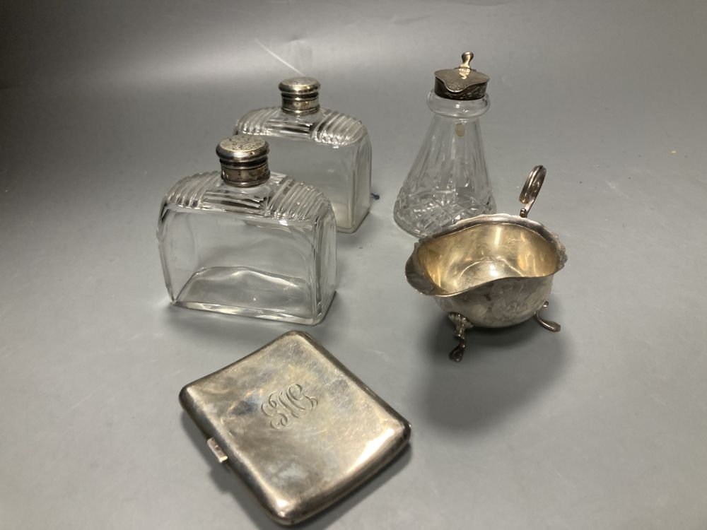 A 1930s silver mounted glass whisky tot jug, 10.3cm, a silver sauceboat , silver cigarette case, etc.